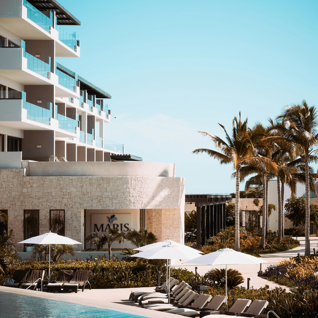 Luxury resort with pool and palm trees under a clear sky.