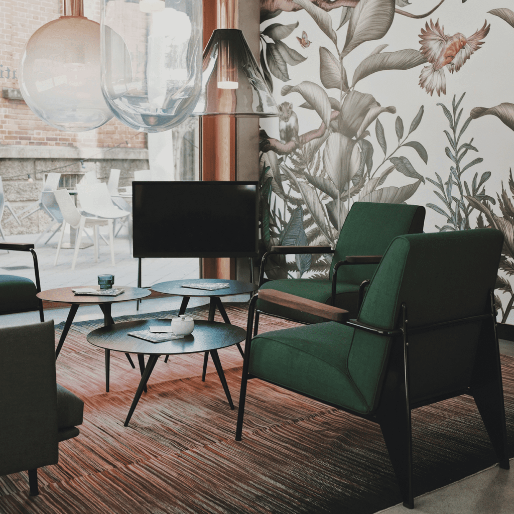 Cozy modern living room with green armchairs and botanical wallpaper.