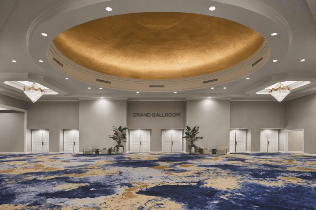 Elegant hotel ballroom entrance with gold ceiling and patterned carpet.