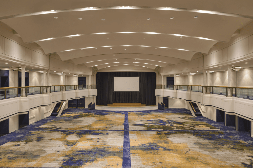 Empty modern conference hall with a stage and patterned carpet.